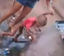 Criança no quintal da casa sendo segurada pela mãe. (Foto: Reprodução | A Princesinha News)