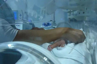 Enfermeira troca recém-nascido entro de incubadora neonatal (Foto: Divulgação UFGD)