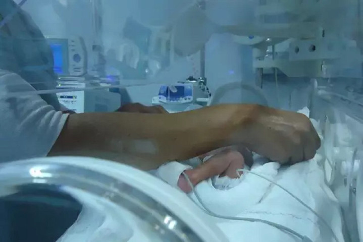 Enfermeira troca recém-nascido entro de incubadora neonatal (Foto: Divulgação UFGD)
