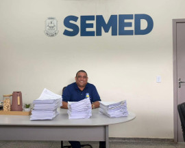 Secretário municipal de Educação, Nilson Francisco da Silva, ao lado de pilhas de contratos que com a digitalização serão coisas do passado. Foto: Divulgação/Assecom
