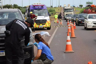 Peritos analisam veículo com corpo de mulher ao fundo. Trânsito ficou lento (Foto: Osmar Veiga/Campo Grande News)