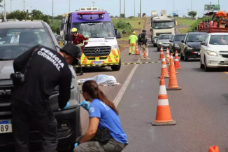 Peritos analisam veículo com corpo de mulher ao fundo. Trânsito ficou lento (Foto: Osmar Veiga/Campo Grande News)